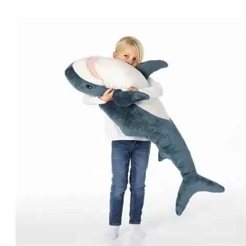 a kid holding a kawaii japanese shark plush toy
