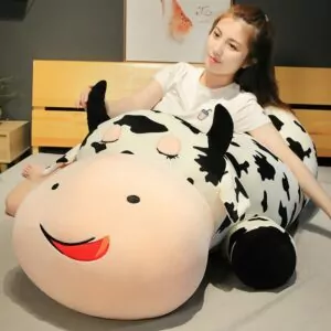 Woman sitting beside a giant stuffed cow