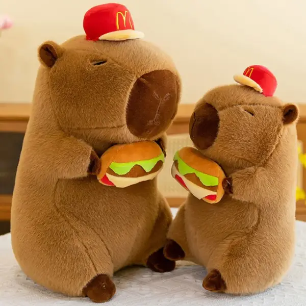 Two capybara plush toys wearing red hats, each holding a plush hamburger, sitting on a white surface.