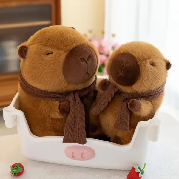 Two brown capybara plush toys with knitted scarves sitting in a white basket, surrounded by strawberries and flowers.