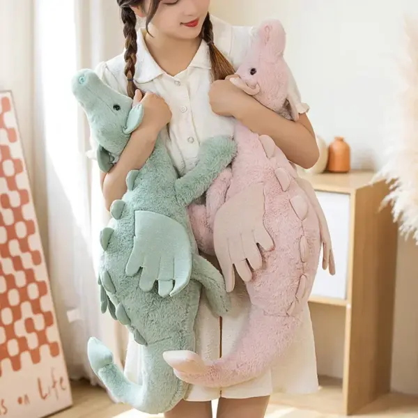 A young woman holding two pastel-colored dragon stuffed animals, one green and one pink, in a cozy room.