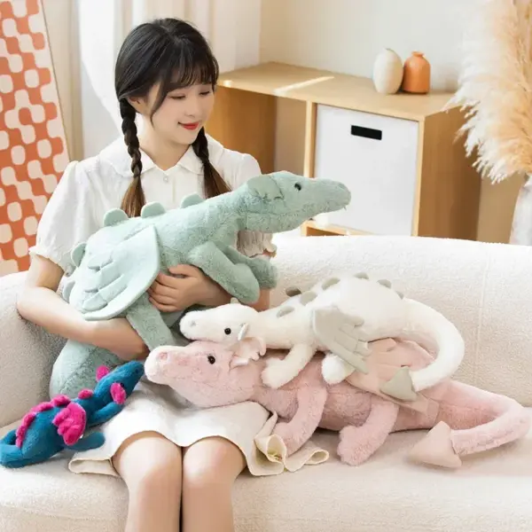 A young woman sitting on a couch with a collection of soft dragon stuffed animals in various pastel colors.